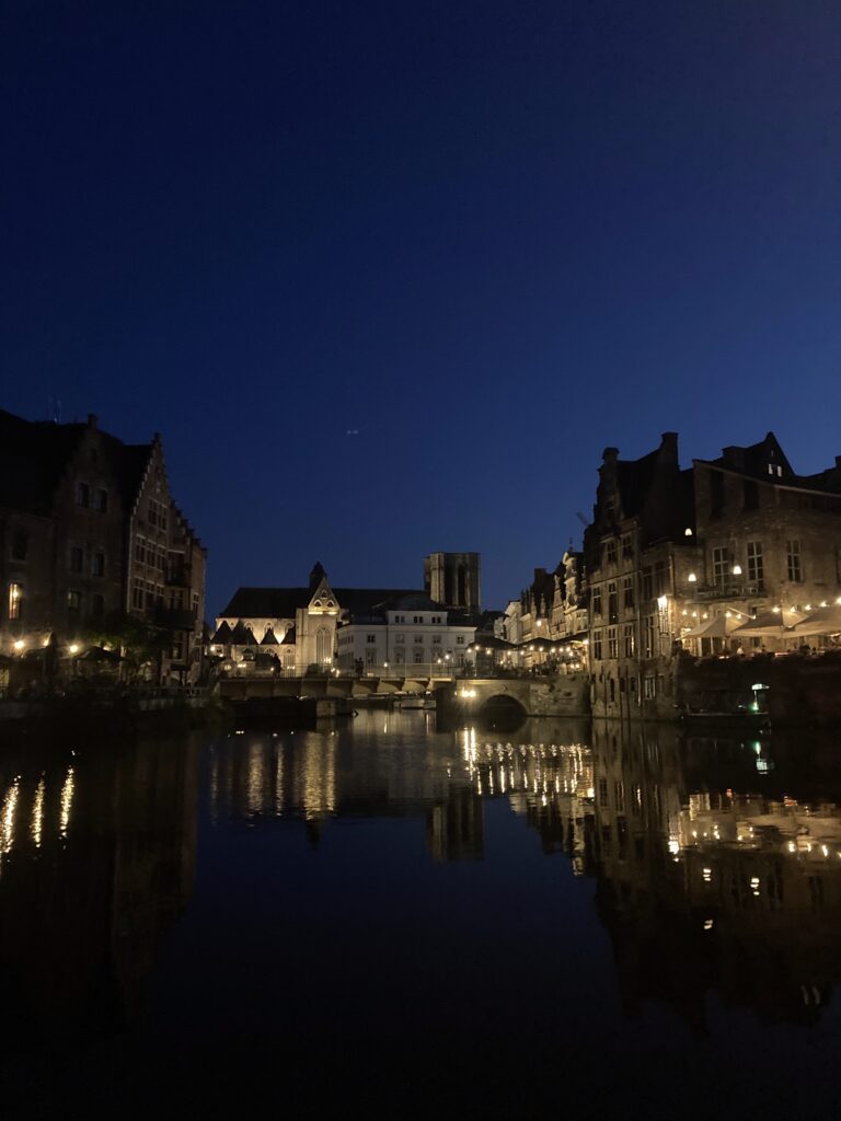 Ghent canal at night with historic medieval buildings and reflections on water, illustrating the city's vibrant urban environ